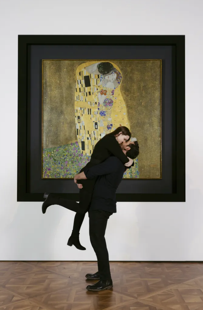 Couple kissing in front of Klimt's painting The Kiss in Belvedere museum Vienna