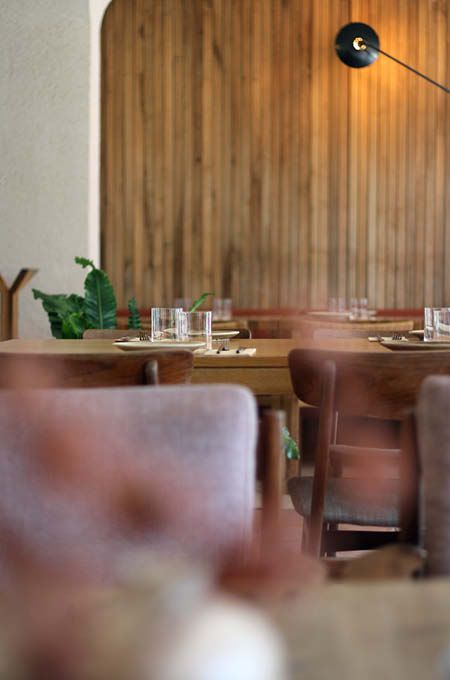 Interior of Green Spot Barcelona featuring wooden wall panels, neatly set dining tables, upholstered seating, and warm ambient lighting.