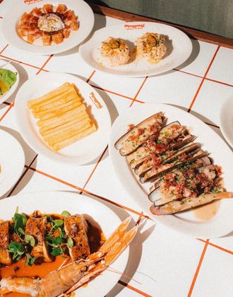 Assorted tapas dishes served on white plates arranged on a tiled table at Bar Pimentel.