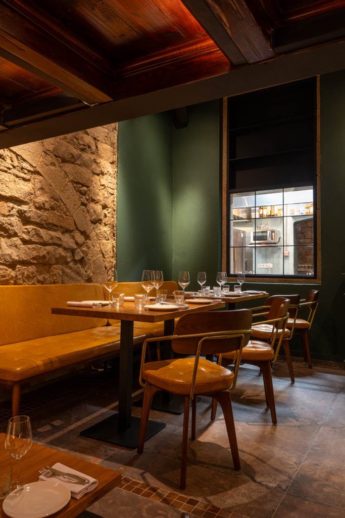 Warmly lit dining area at Bornes restaurant featuring wooden tables and chairs, exposed stone walls, and an intimate interior design.