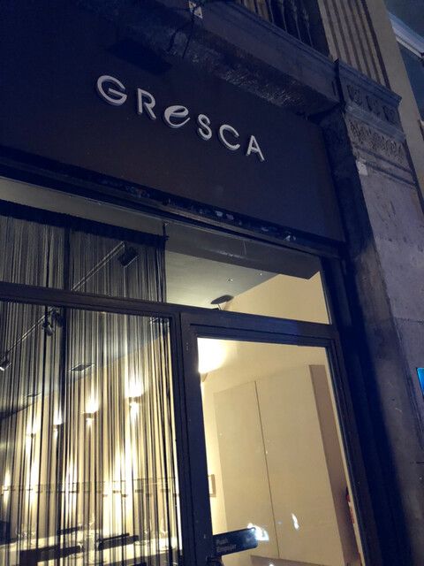 Entrance of Gresca restaurant in Barcelona with illuminated signage and a contemporary storefront at night.