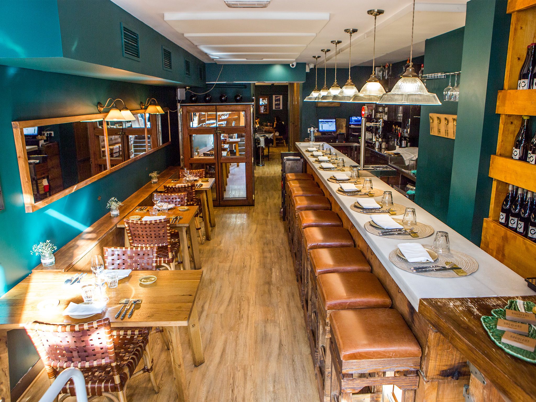 Interior of Suculent restaurant in Barcelona featuring a long dining counter, wooden furnishings, and warm ambient lighting.