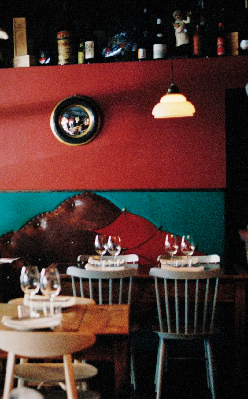 Interior of Xemei restaurant in Barcelona featuring vintage décor, wooden tables, and warmly lit dining seating.